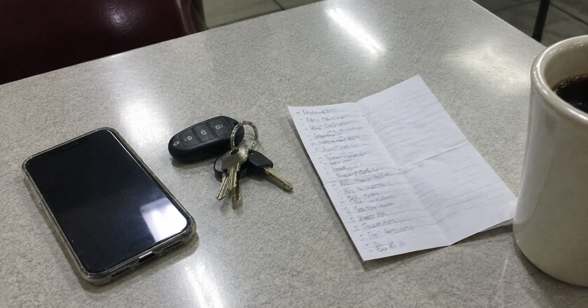 Phone snapshot of a late-night diner table: a phone, van keys, a folded setlist and a mug of coffee.